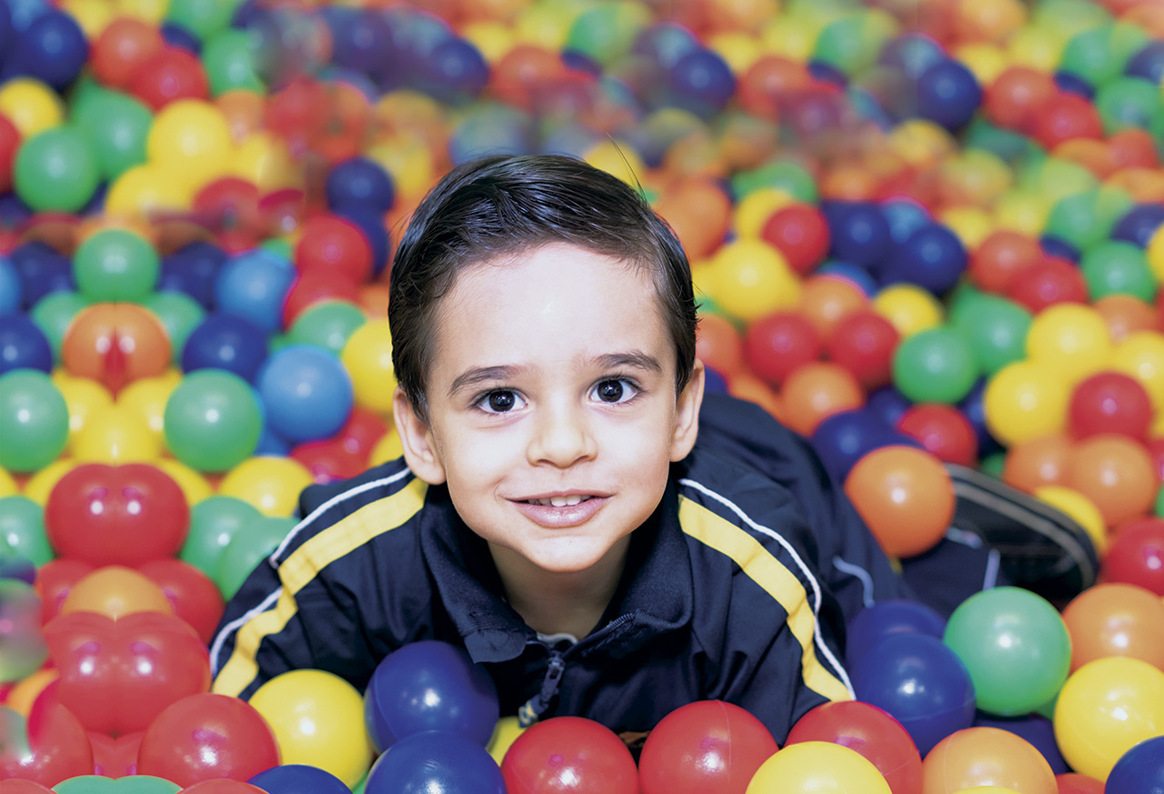 Imagem de aluno do Objetivo dentro de uma piscina de bolinhas